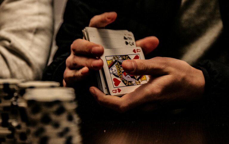 A person holding a card in front of a table with poker chips